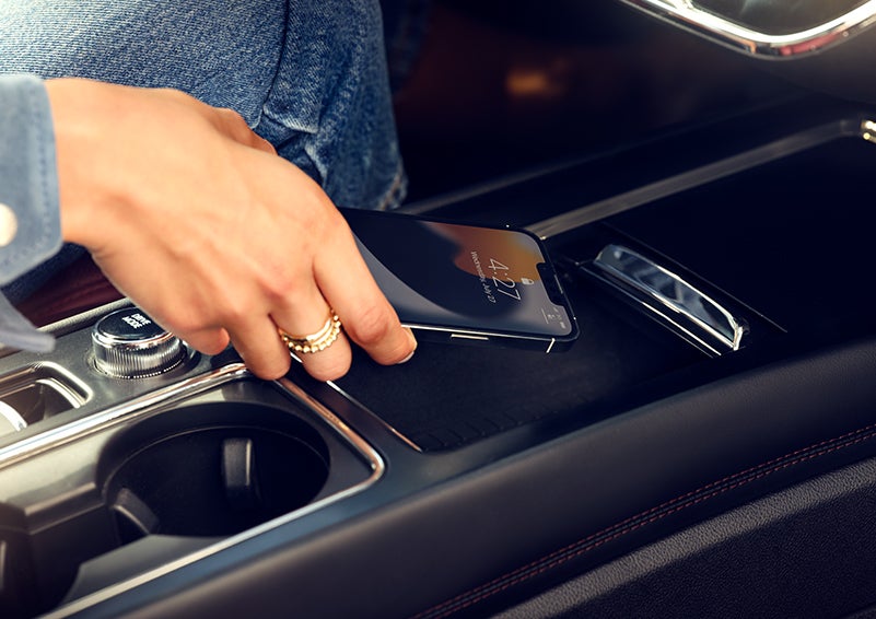 A smartphone is is being placed on the wireless charging pad in the front center console cubby. | Gates Ford Lincoln in Richmond KY